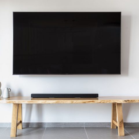 a flat screen tv mounted on wall over a wooden console